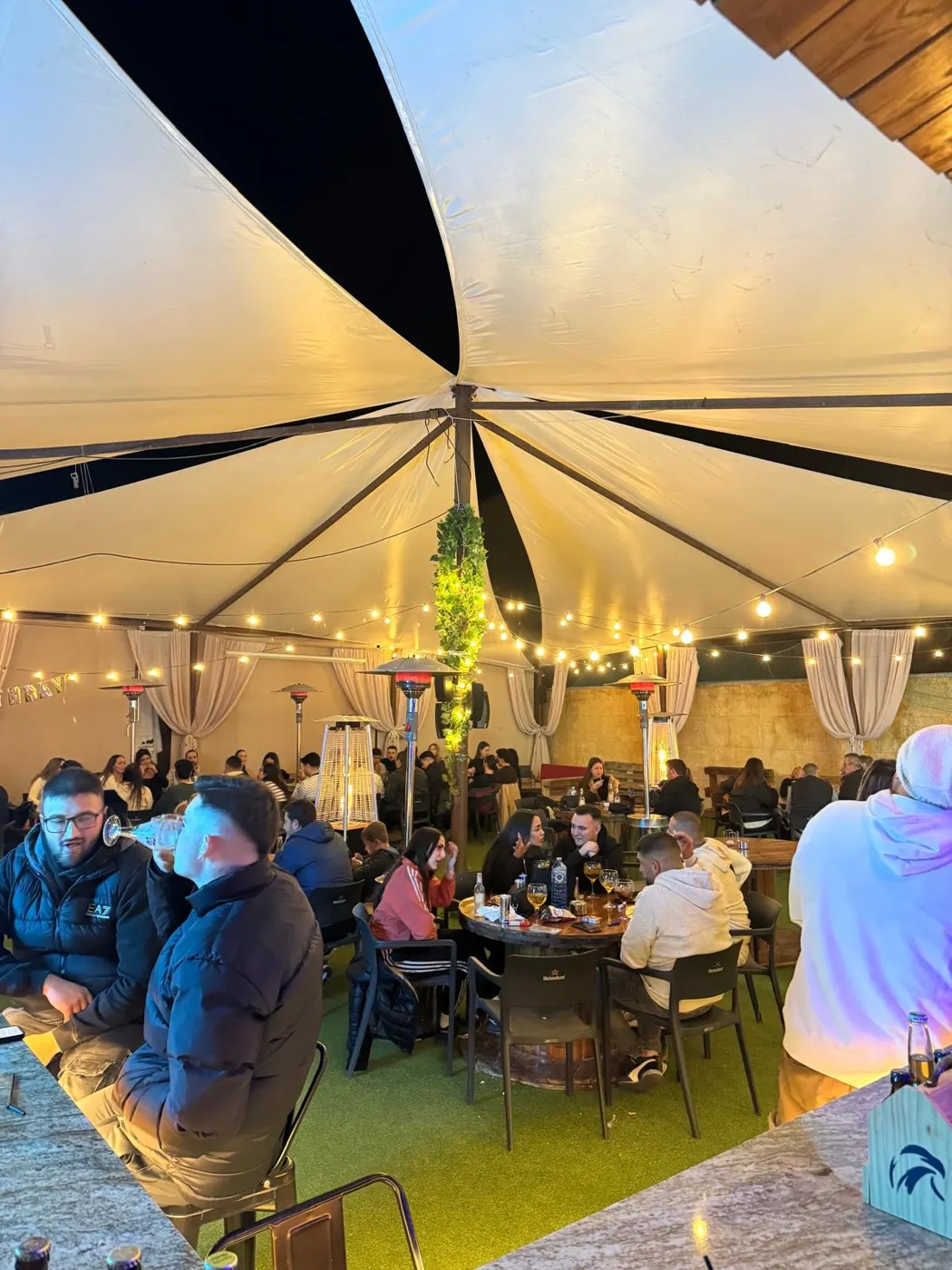 Terraza chill out de noche con guirnaldas de luces y estufas