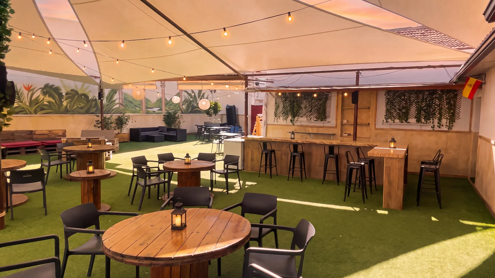 Terraza chill out al atardecer con guirnaldas encendidas y farolillos en las mesas