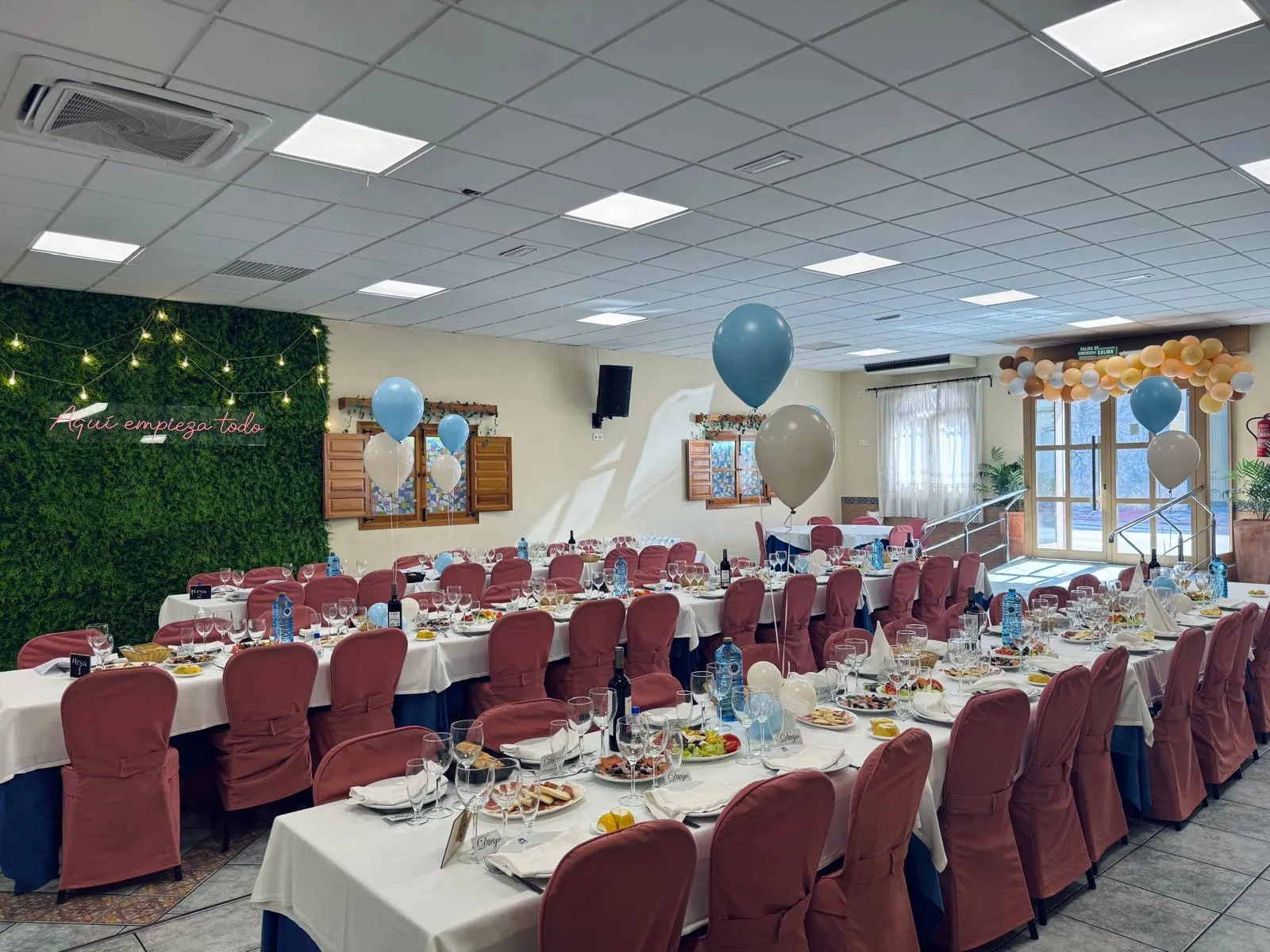 Salón preparado para una comunión con globos y jardín vertical
