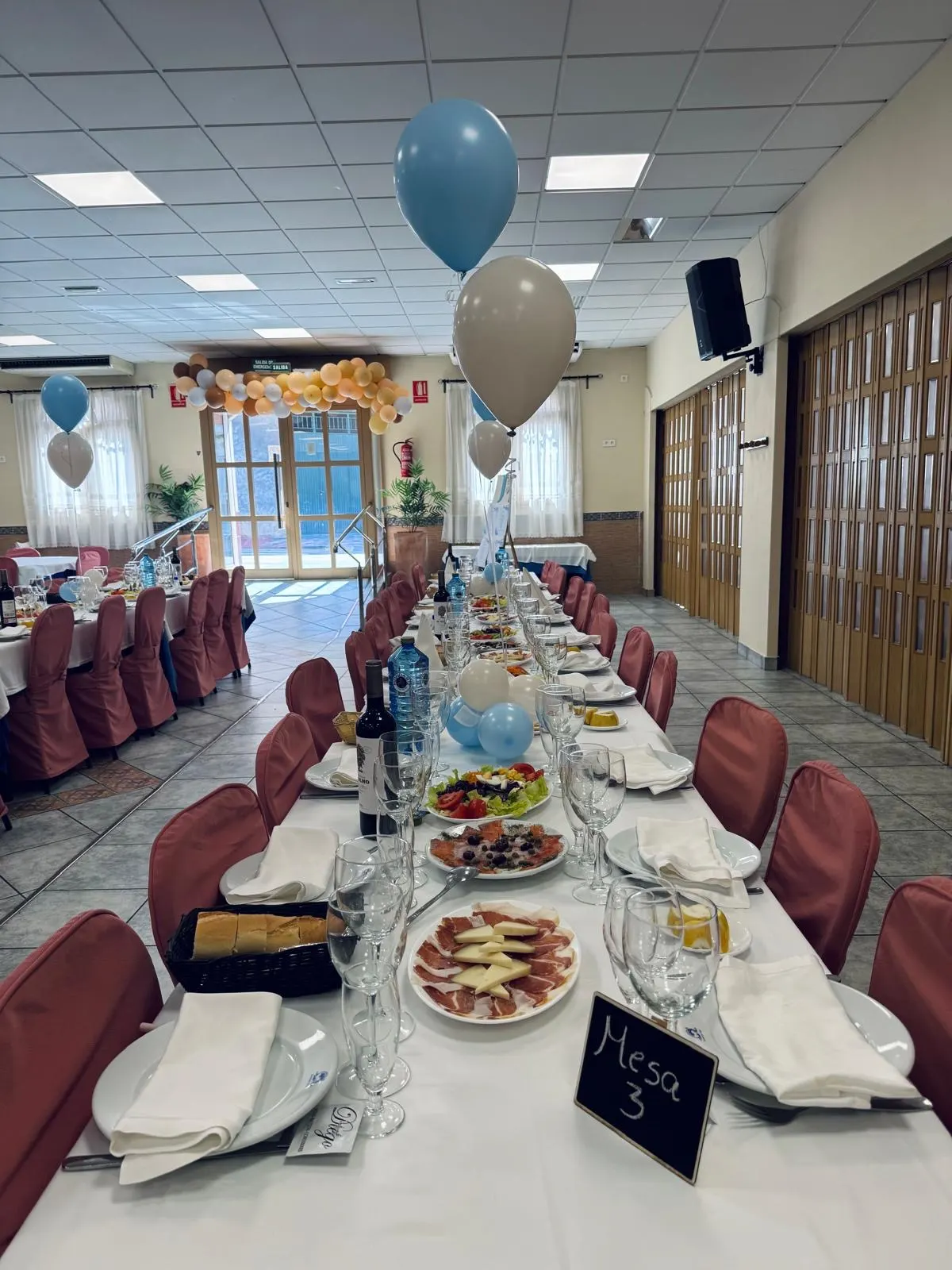 Mesa larga con entrantes y globos para una comunión