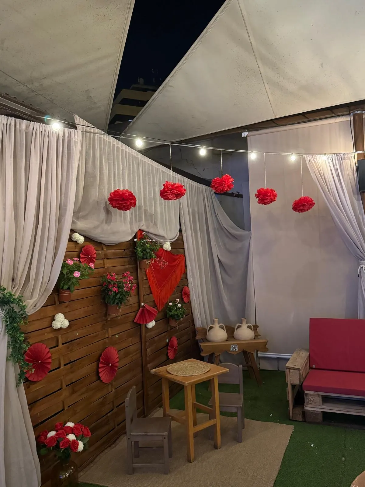 Rincón decorado de feria con mantón, abanicos y flores
